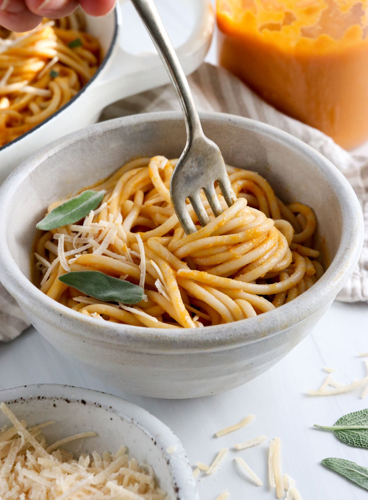 fork twirling the pumpkin pasta in a white bowl