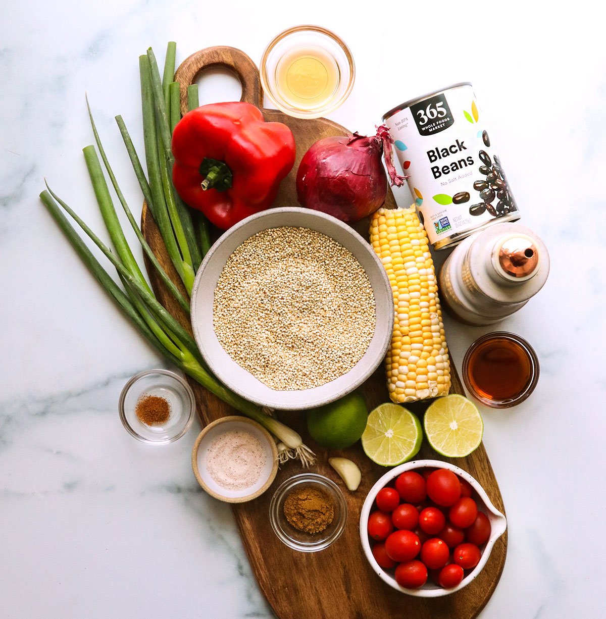 quinoa, corn, green onion, cherry tomatoes, red onion, and black beans on a board.