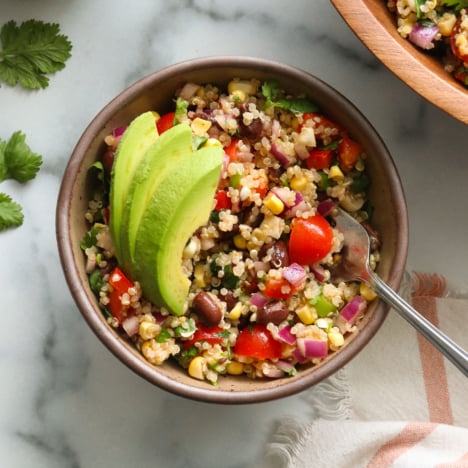 quinoa black bean salad bowl topped with avocado.