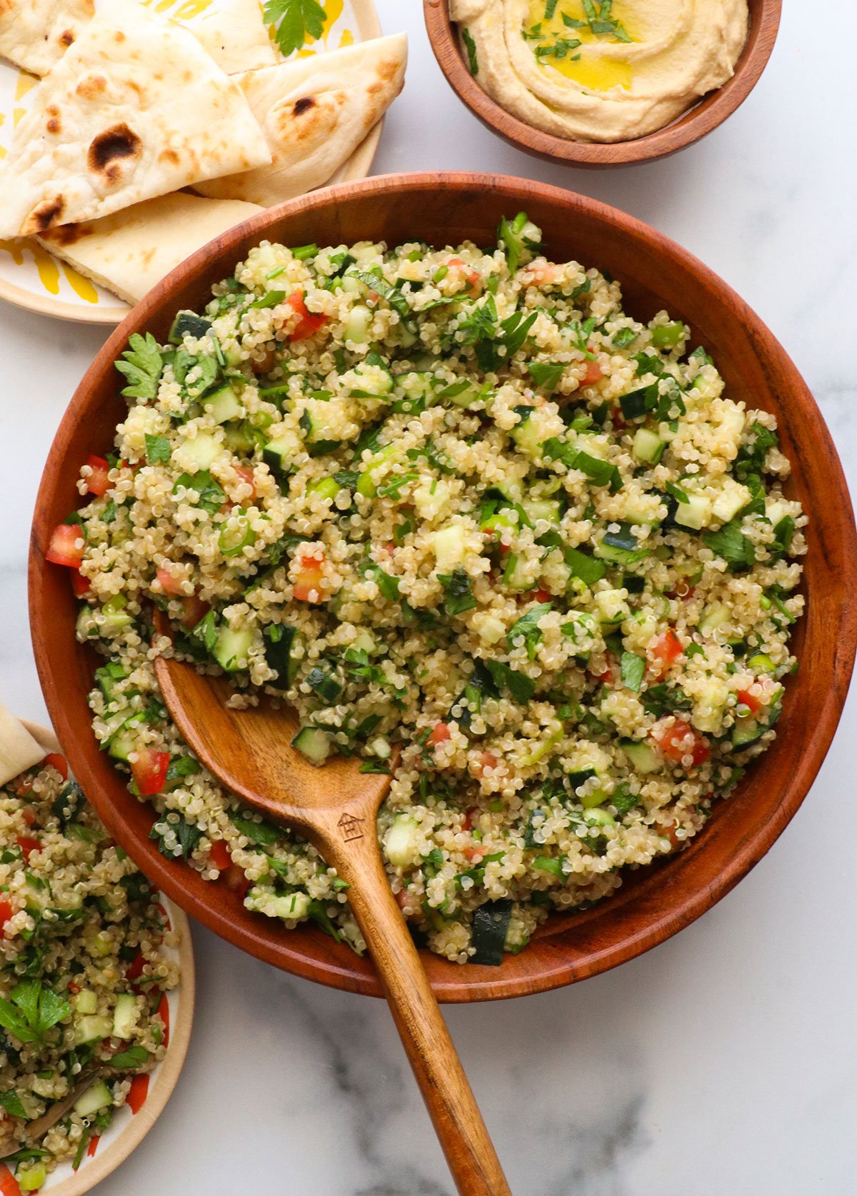 quinoa tabbouleh served in a wooden bowl with a wooden spoon.