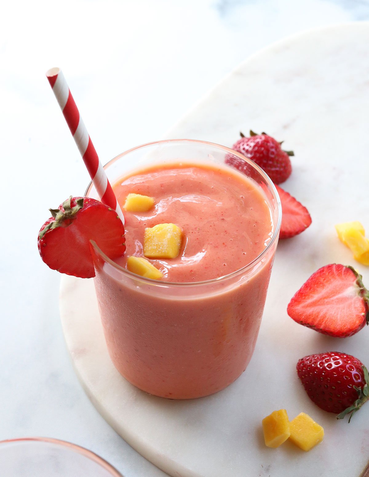 strawberry mango smoothie served with a red and white striped straw.