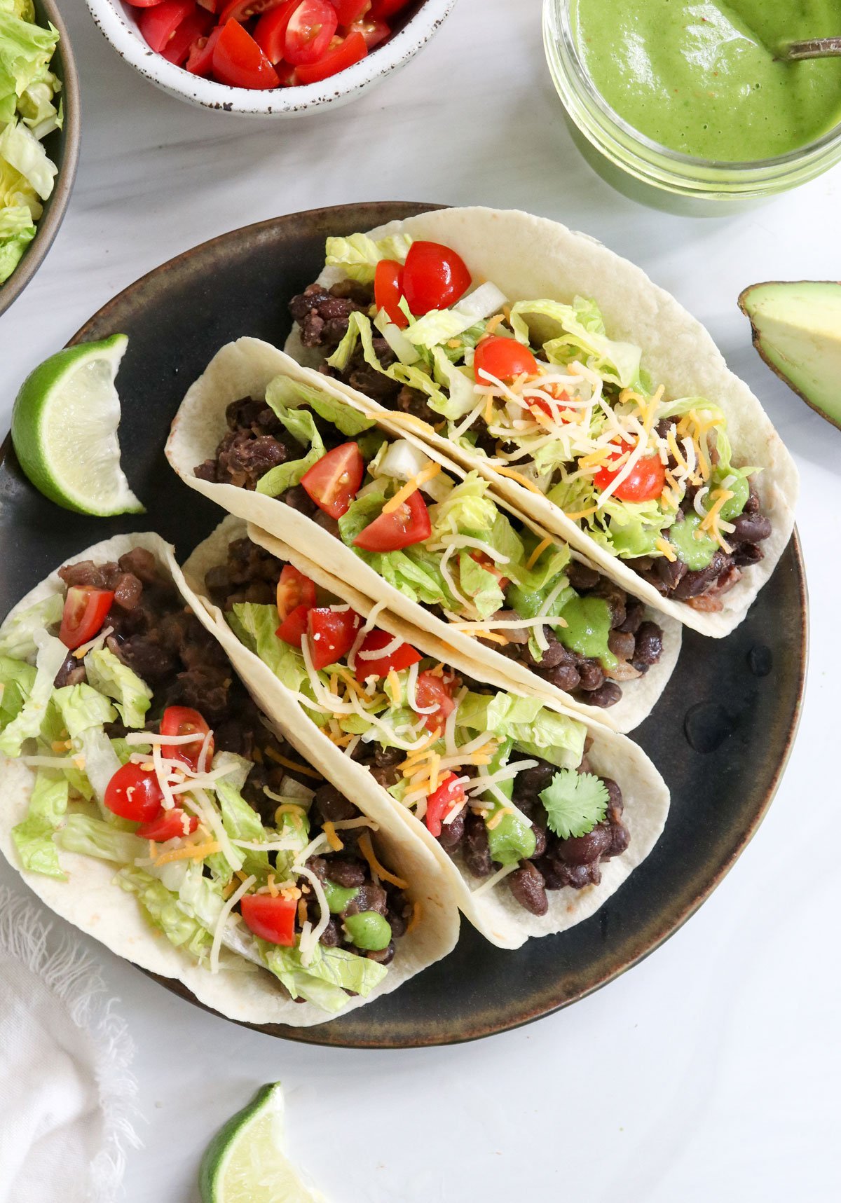 finished black bean tacos with shredded cheese on top.