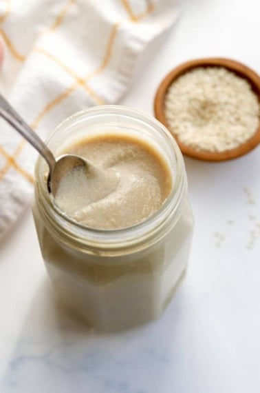 tahini in a glass jar with spoon