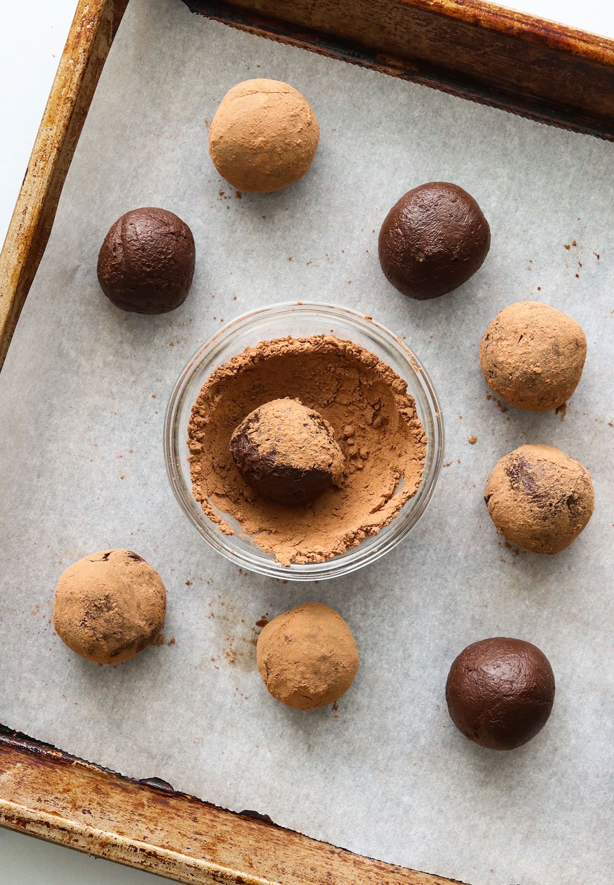 avocado truffles on a baking sheet rolled in cocoa powder.