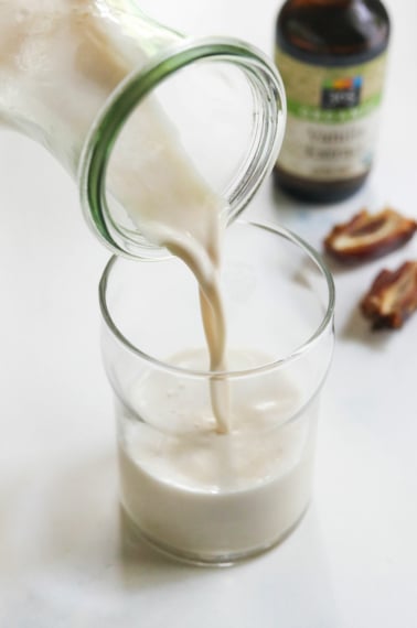 vanilla almond milk poured into glass with dates in background