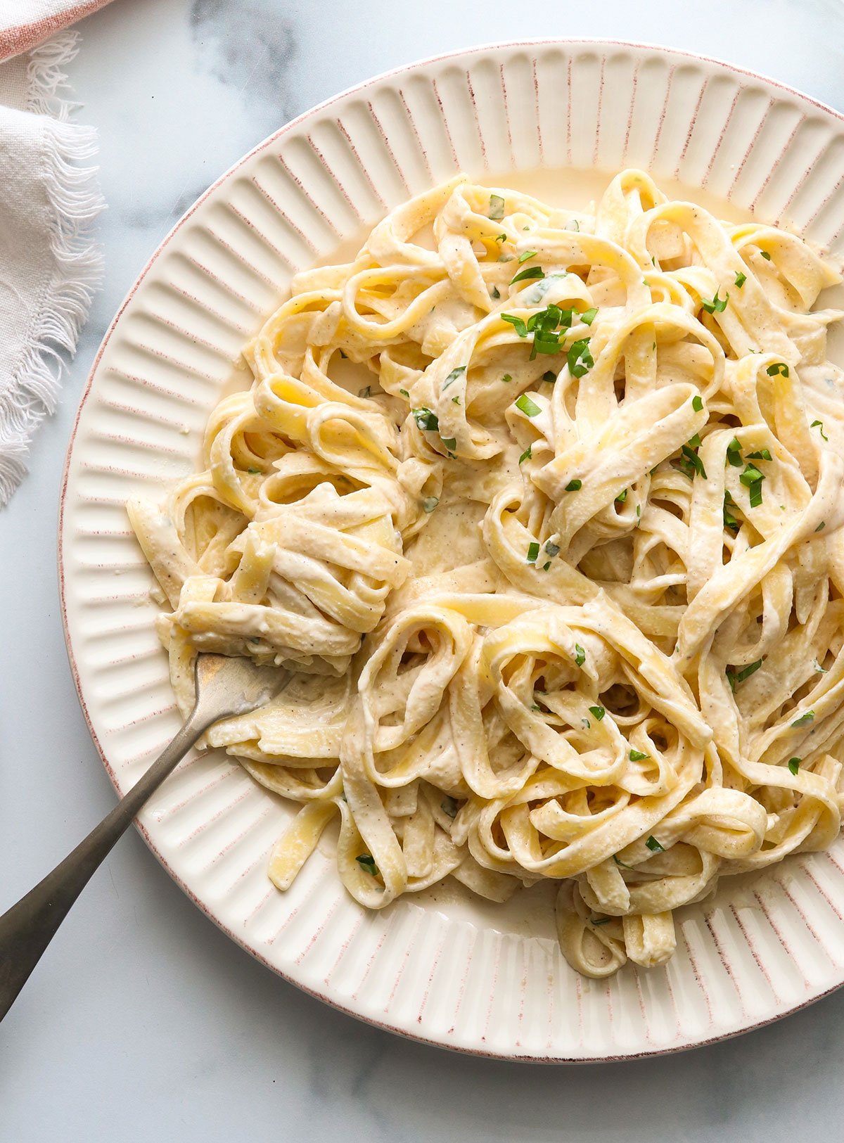 vegan alfredo sauce over noodles and twirled on a fork.