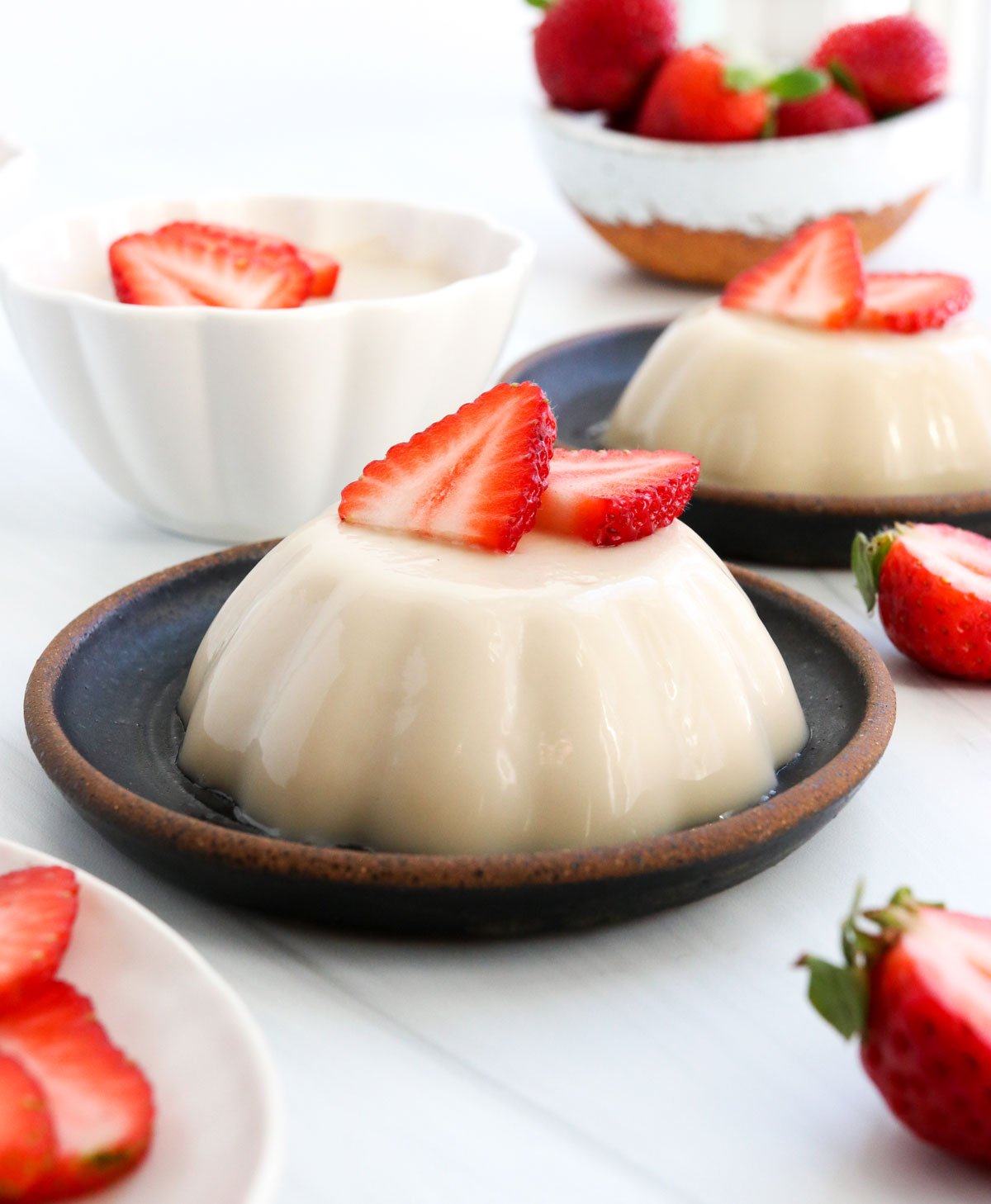 panna cotta served on a plate with strawberries.