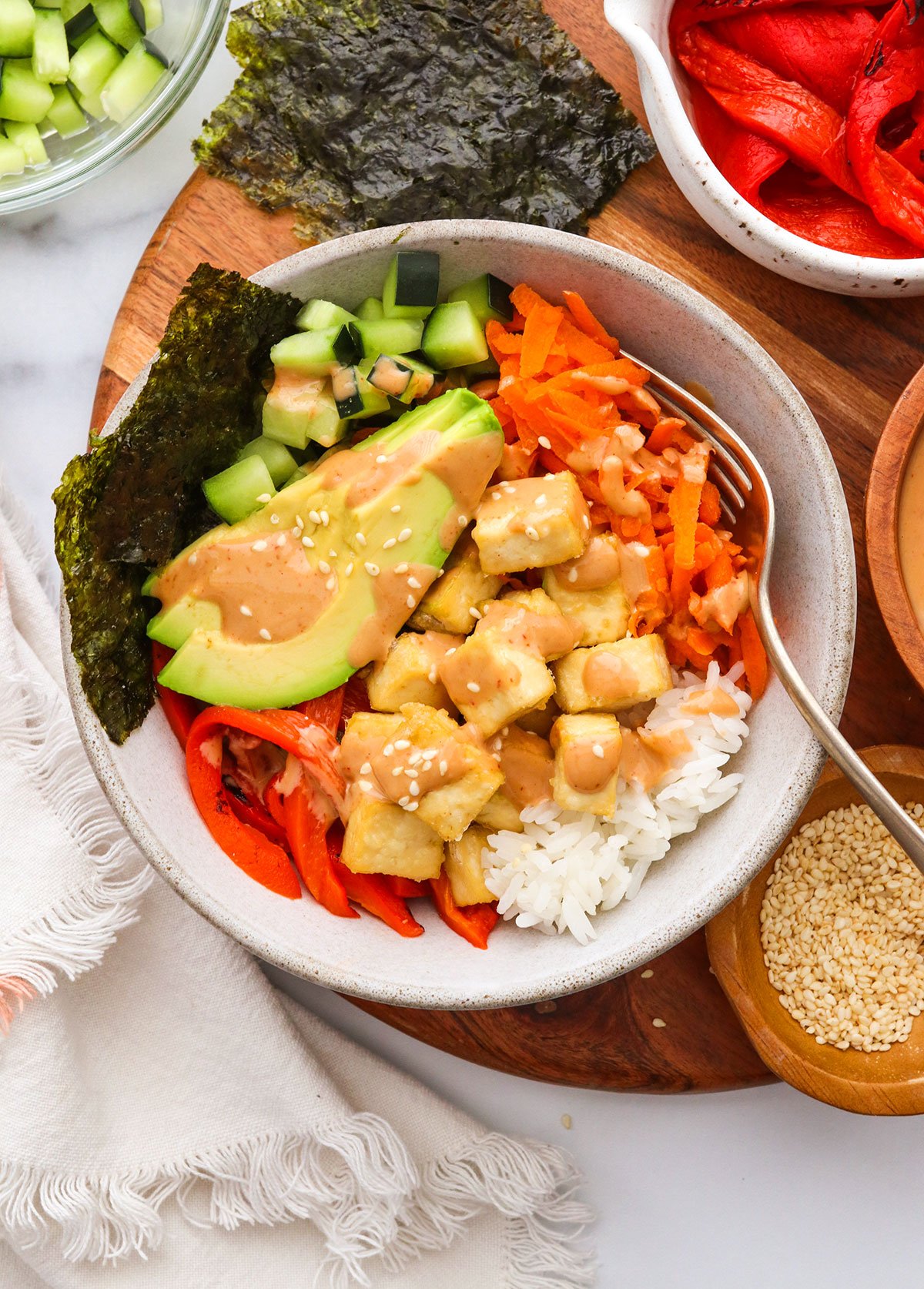 vegan sushi bowl topped with creamy tahini sriracha sauce.