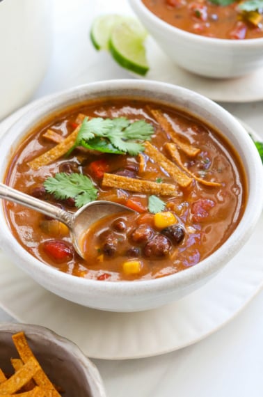 tortilla soup lifted from the bowl on a spoon.