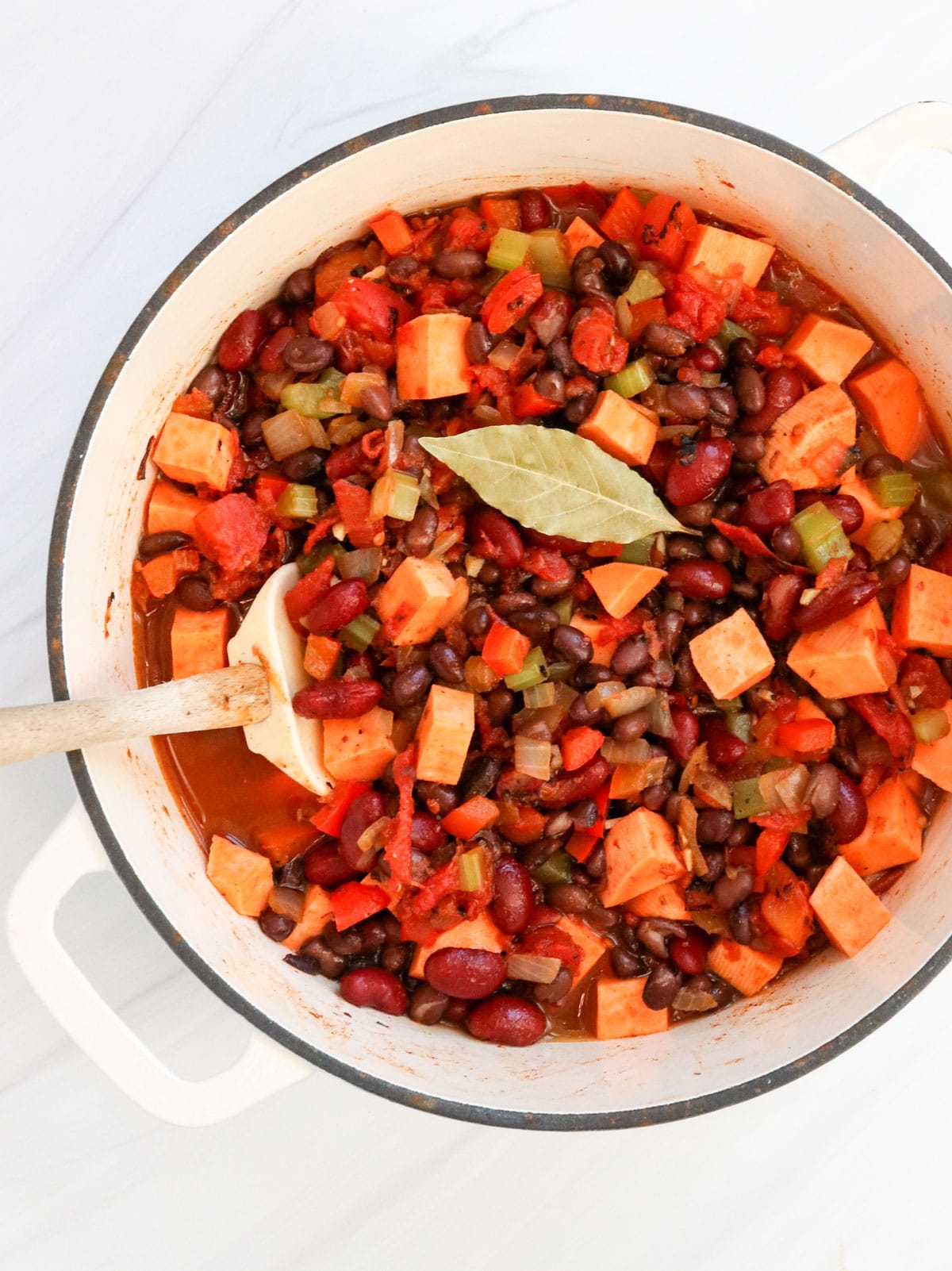 chili ingredients in white pot with bay leaf on top