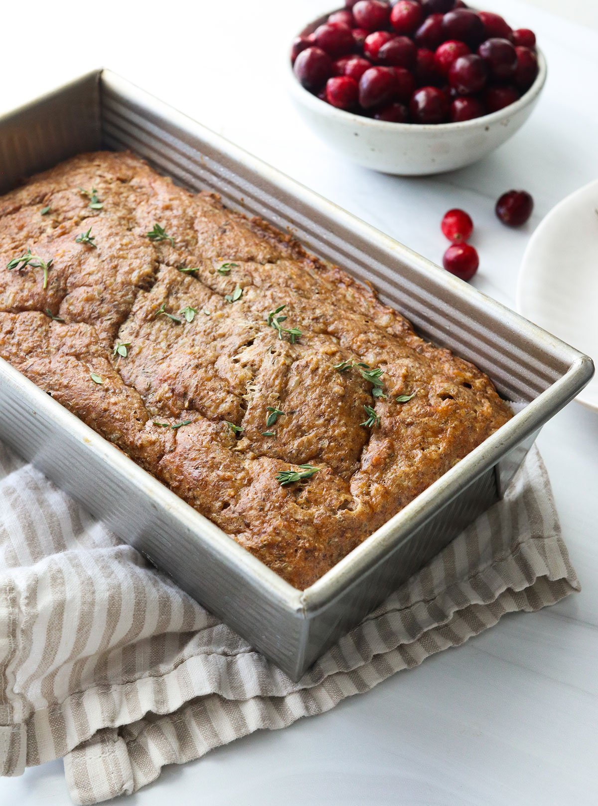 veggie meatloaf in a loaf pan topped with fresh thyme.