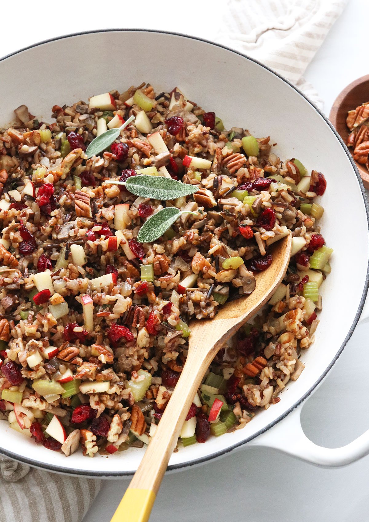 wild rice stuffing in a white skillet topped with fresh sage.